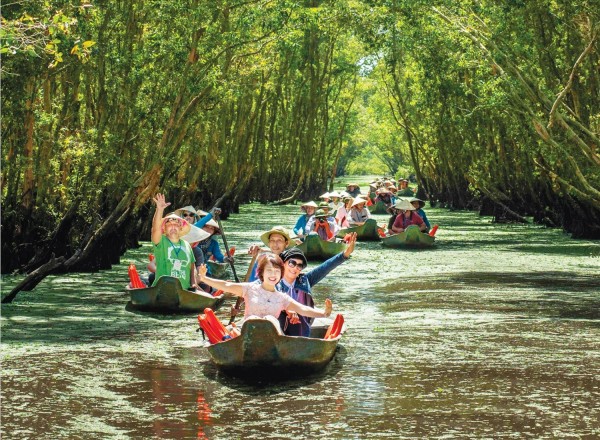 Chiếc xuồng ba lá lướt nhẹ theo từng nhịp dầm khua nước giữa hai hàng tràm rợp bóng xanh mát tạo cảm giác thư thái cho khách du lịch khi trải nghiệm. (Trong ảnh: Du khách trải nghiệm tại khu du lịch sinh thái Gáo Giồng, huyện Tháp Mười, tỉnh Đồng